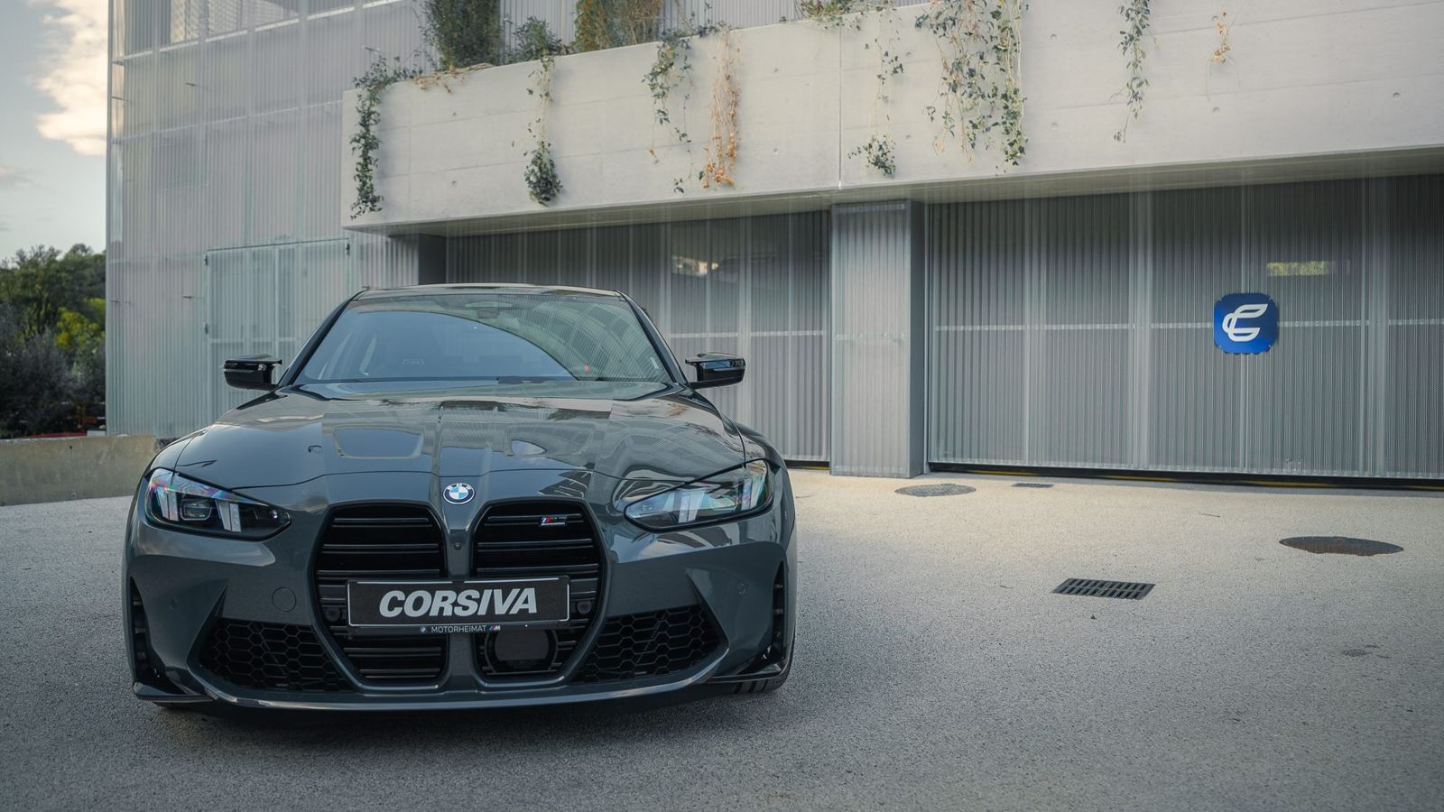 BMW M3 Compétition devant la porte des box Corsiva